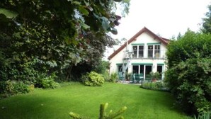 A two-story house with a well-maintained lawn and a large tree in the foreground. - "Nice living in Mainz" Apartment Gisela & Jürgen Will  (Gonsenheim)