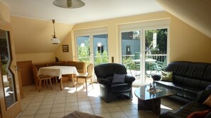 A spacious living room with a dining area, a black leather sofa, a coffee table, and a patterned rug. - "Nice living in Mainz" Apartment Gisela & Jürgen Will  (Gonsenheim)
