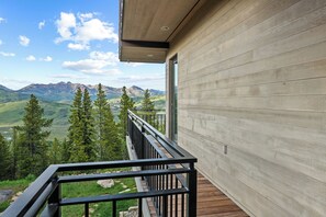 A modern building with a balcony overlooking a mountainous landscape.