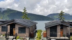 Une rangée de chalets modernes, avec un lac et des montagnes en arrière-plan.