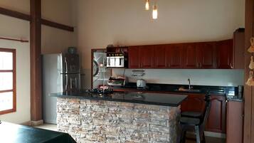 Una cocina con una isla de piedra, electrodomésticos de acero inoxidable y armarios de madera.