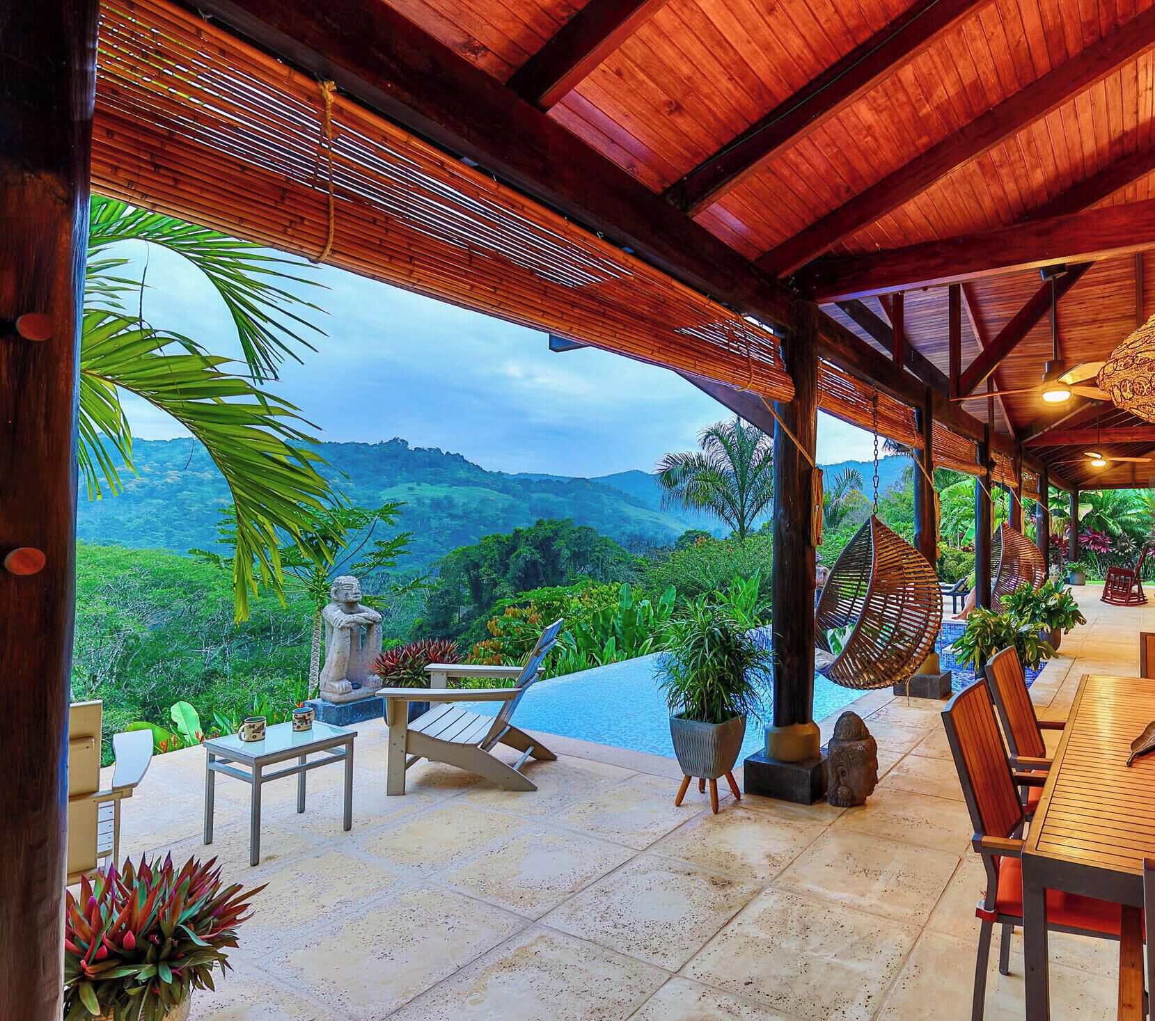 An outdoor seating area with a view of a mountainous landscape, wooden furniture, and a stone statue.
