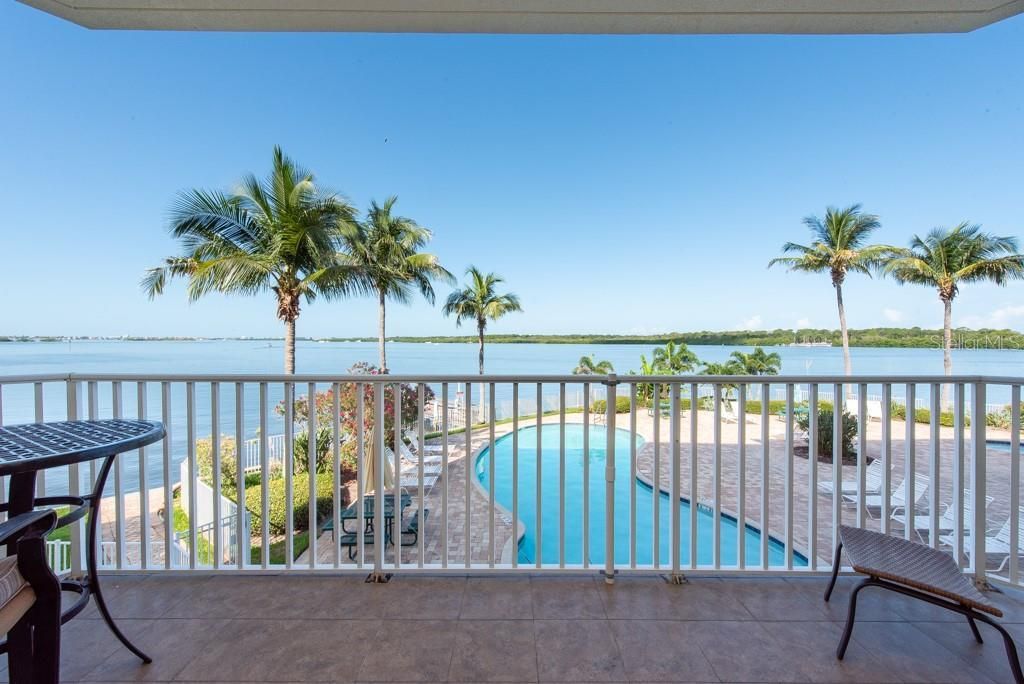 Ein Balkon mit Blick auf ein Schwimmbad und Palmen.