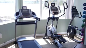 Een sportschool met loopbanden, een crosstrainer en een hometrainer.