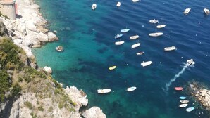 A coastal area with a beach, boats, and rocky terrain. - VILLA SHAH a place to listen to the sea in Amalfi Coast (Conca dei Marini)