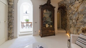 A room with a stone wall, a wooden cabinet, and a white door. - VILLA SHAH a place to listen to the sea in Amalfi Coast (Conca dei Marini)