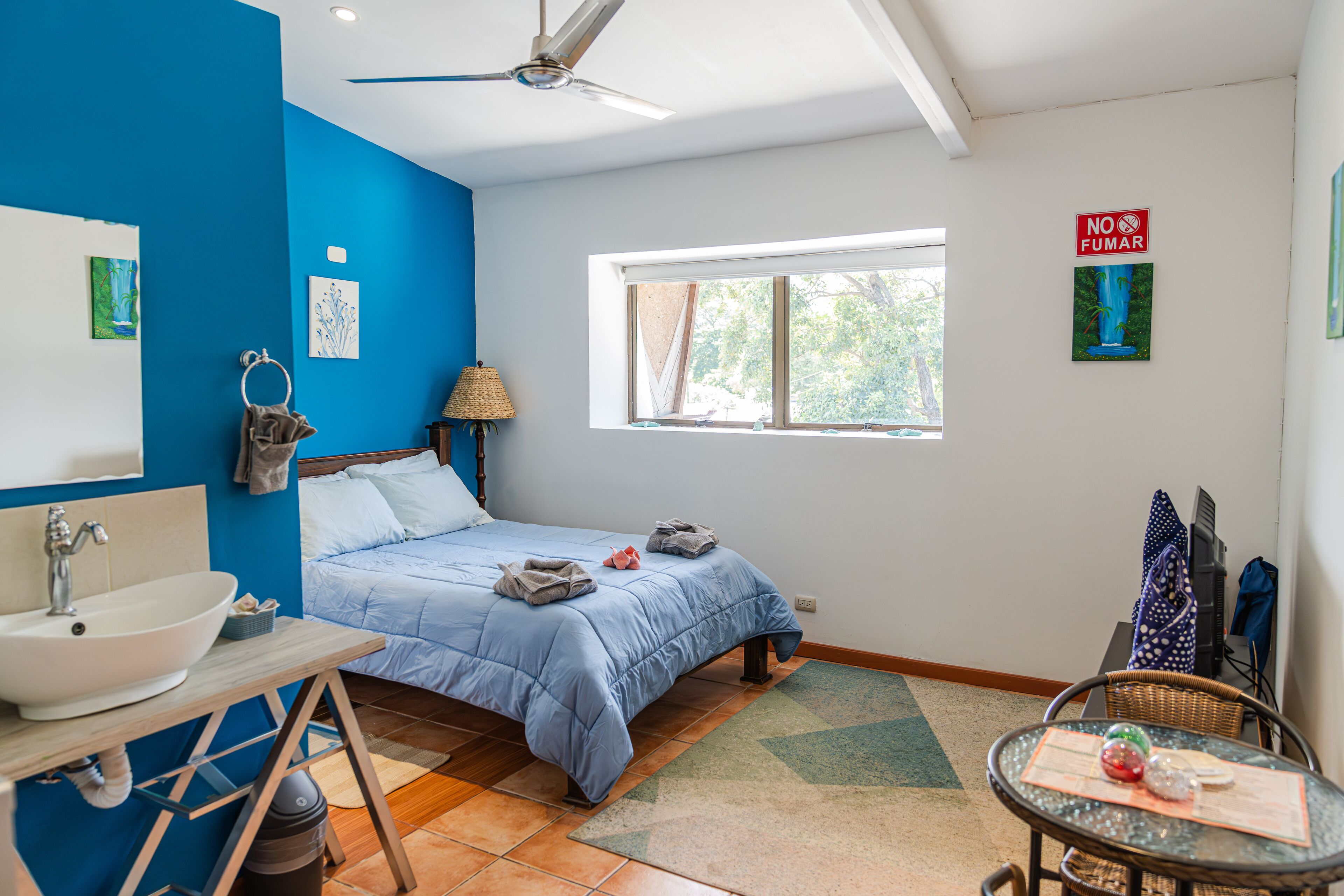 Una camera da letto con un letto, un lavandino, una finestra e una ventola a soffitto.