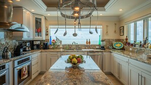 A modern kitchen with granite countertops, stainless steel appliances, and a central island with fruit. - Luxury Home King Beds Ocean View 5 Min To Sandbar, Best Keys Experience! (Tavernier)