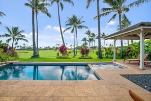 Ein Pool mit Blick auf einen Golfplatz und Palmen.
