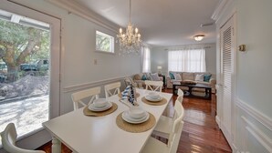 A dining area with a white table set for four, a chandelier, and a view of the outdoors.