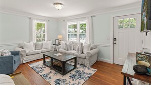 A living room with two light-colored sofas, a wooden coffee table, and a floral rug.