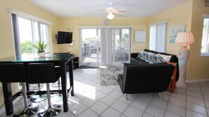A living room with a sofa, a coffee table, a TV, and a ceiling fan. - By The Sea ~ Islamorada Home with Ocean Views! (Islamorada)