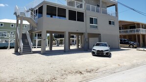 A multi-story building with a staircase, balconies, and a car parked in front. - By The Sea ~ Islamorada Home with Ocean Views! (Islamorada)
