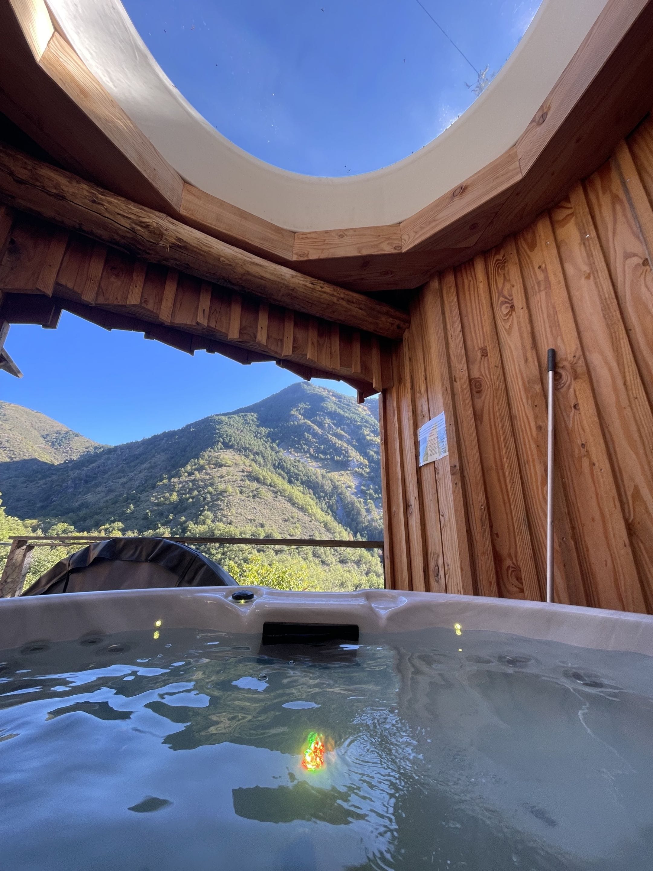 Una cabaña de madera con jacuzzi y vistas a las montañas.