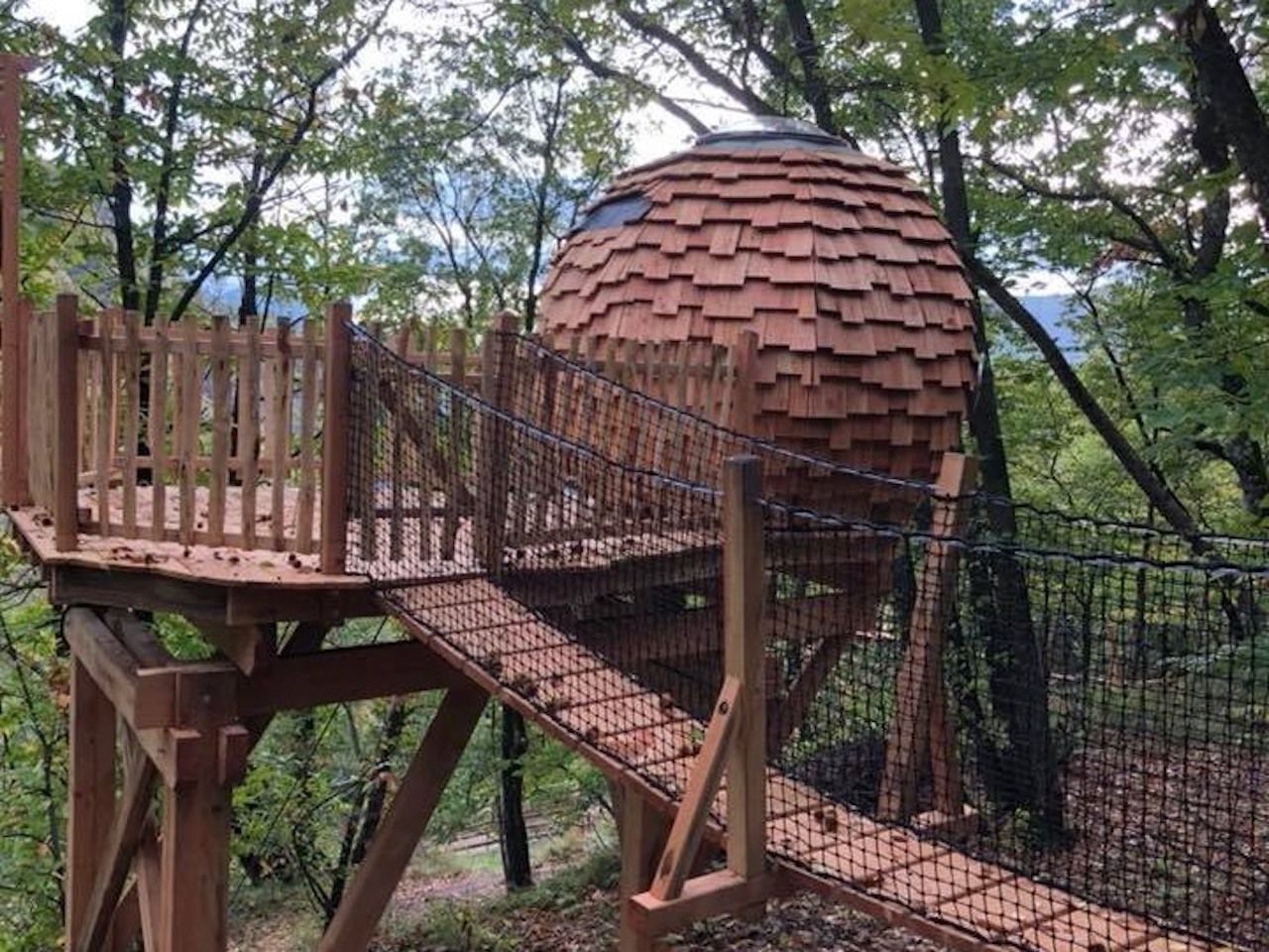 Een houten uitkijktoren met een hekkenloopplateau dat leidt naar een bolvormige constructie.
