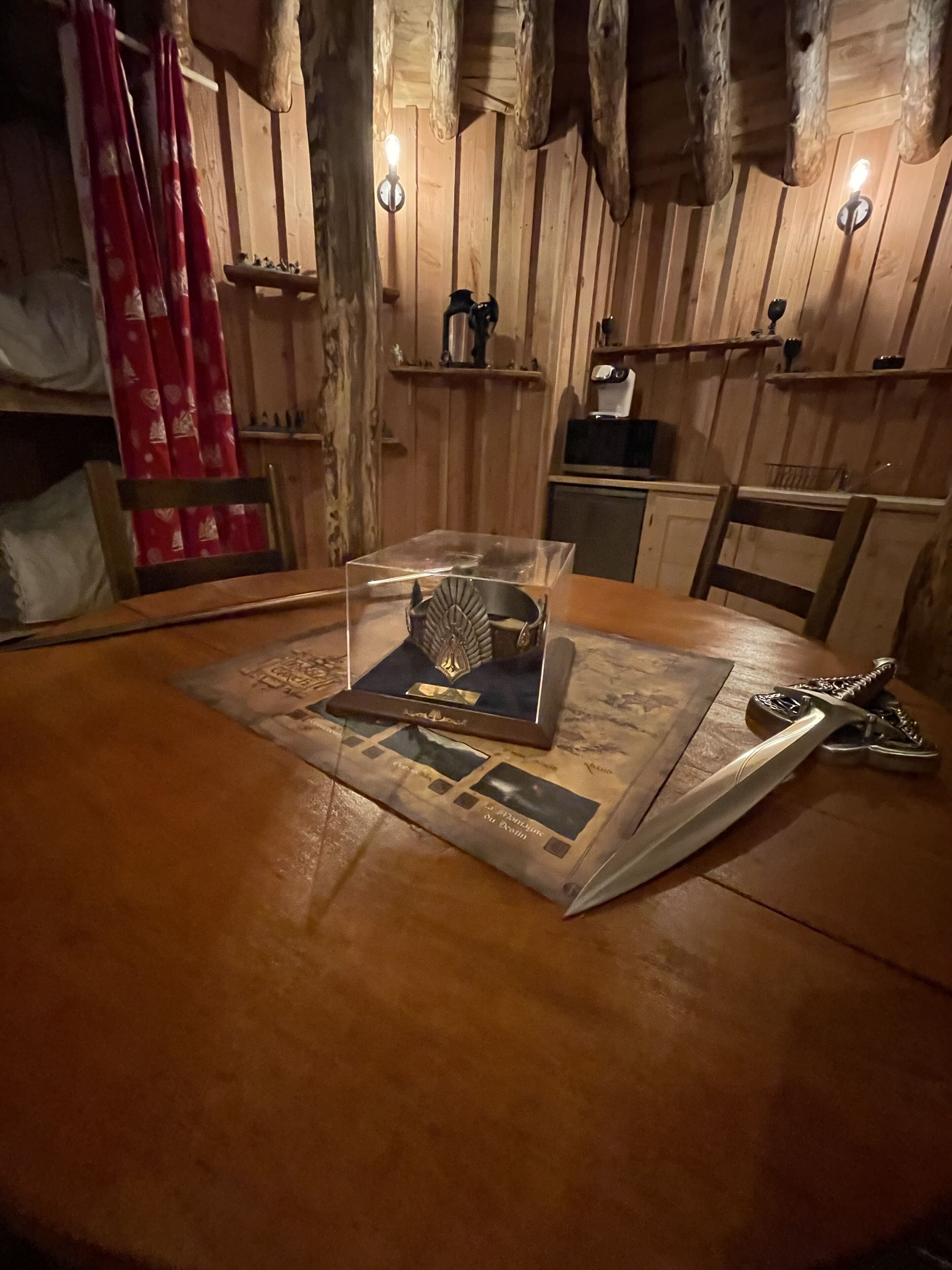 Un intérieur en bois avec une table sur laquelle sont exposés une épée et un livre.