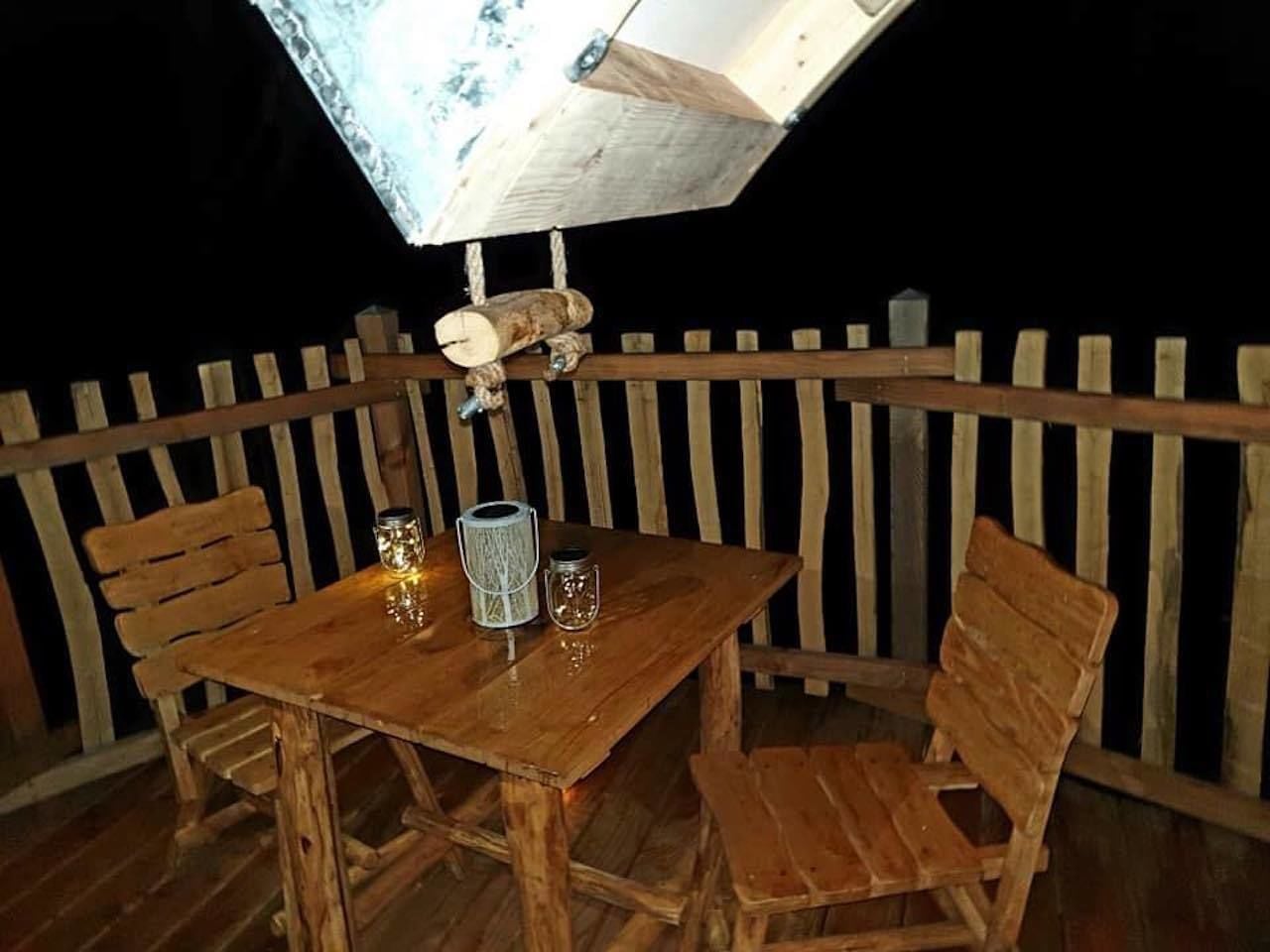 Une table et des chaises en bois sont disposées à l’extérieur, avec une clôture en bois en arrière-plan.