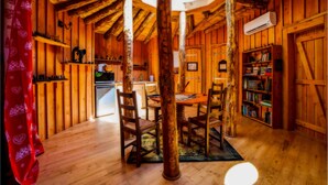 A rustic wooden interior with a dining area, bookshelves, and a ceiling fan. - Les Ecrins de Belvedere (Belvedere)
