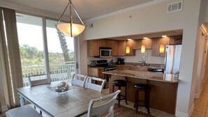A modern kitchen with a dining area, wooden flooring, and large windows. - Sleek & Stylish- Riverside (Pensacola)