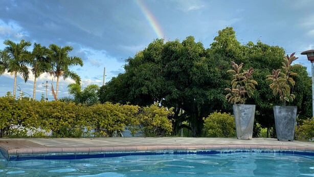Una piscina bajo un cielo azul despejado y un arcoíris.