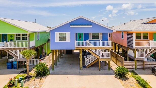 Une rangée de maisons de plage colorées, dotées de terrasses en bois et d’escaliers menant à l’entrée.