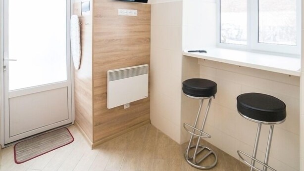 A modern bathroom with a wooden vanity, a built-in heater, and two bar stools. - Smart Apartment Kulisha 29v (Lviv)