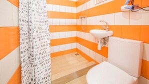 A bathroom with orange and white tiles, a white sink, and a shower. - Smart Apartment Kulisha 29v (Lviv)