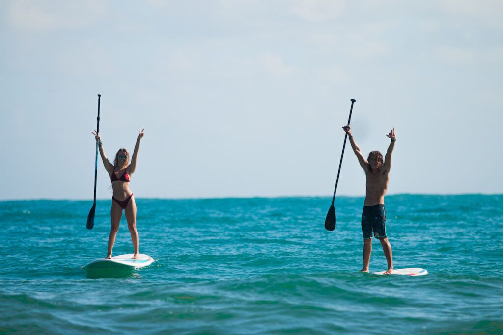 Zwei Personen stehen auf Paddleboards auf ruhiger See.