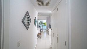 Un couloir avec un lit, une petite table et un téléviseur au fond.