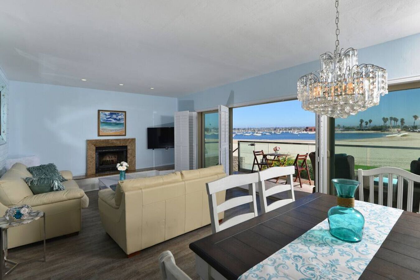 Un salon comprenant un canapé, un téléviseur, une cheminée et un balcon avec vue sur la mer.