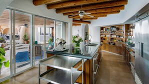 Una cocina moderna con vigas de madera, una isla de vidrio y vistas al área exterior.