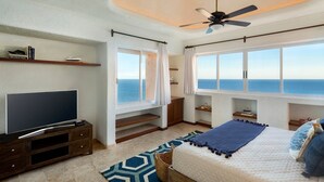 Un dormitorio con una cama grande, televisión y vista al océano.