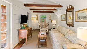 A room with a wooden ceiling, a television, a sofa, a chair, a small table, and a dresser. - Quaint Guest Cottage 1 block from Beach updated July 2022 (Saint Simons Island)