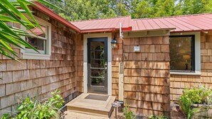 A wooden house with a red roof, a front door, and a small porch. - Quaint Guest Cottage 1 block from Beach updated July 2022 (Saint Simons Island)