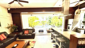 Un salón moderno con sofá, una mesa de centro y vistas a una piscina y vegetación.