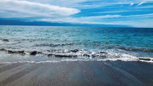 Una playa con agua azul cristalina y una orilla arenosa.