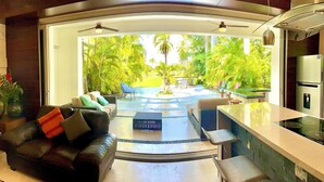 Una sala de estar moderna con sofá, mesa de centro y área de cocina con encimera y electrodomésticos.