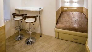 A compact bedroom with a bed, a desk, and two bar stools. - Smart Apartment Chornovola 21a (Lviv)