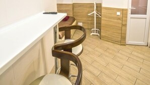 A bathroom with a white sink, two wooden bar stools, a towel rack, and a door. - Smart Apartment Chornovola 21a (Lviv)