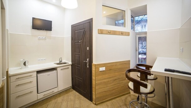 A modern kitchen with a built-in dishwasher, a wooden door, a mounted TV, and a bar area with stools. - Smart Apartment Chornovola 21a (Lviv)