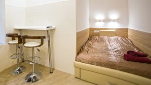 A small room with a bed, a table, and two stools. - Smart Apartment Chornovola 21a (Lviv)