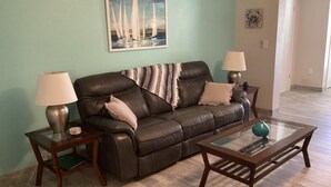 A living room with a brown leather sofa, two lamps, a glass coffee table, and a painting on the wall. - Sunsational Seahorse- Nice and Relaxing
2/2 Sleeps 6 (New Port Richey)