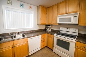 A kitchen with wooden cabinets, a microwave, a coffee maker, a dishwasher, and a double oven.