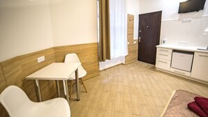 A hotel room with a bed, a dining table with chairs, a kitchen area, and a TV mounted on the wall. - Smart Apartment Chornovola 21b (Lviv)