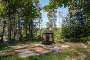 En overdækket pavillon i et skovområde med klar himmel.