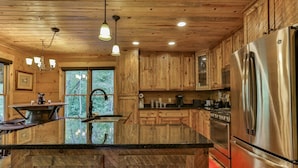 A kitchen with wooden cabinets, a stainless steel refrigerator, and a large island with a sink.