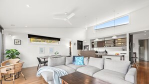 A modern living room with a sectional sofa, a dining table, and a kitchen area with a countertop and cabinets.