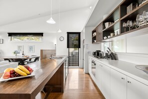 A modern kitchen with a central island, a dining area with a table and chairs, and a view of the outdoors through a window.