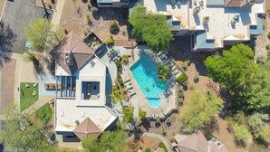 Vue aérienne d’un quartier résidentiel avec de nombreuses maisons, une piscine et des jardins aménagés.