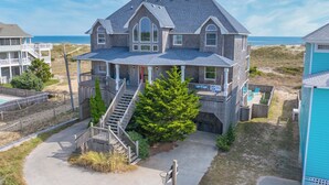 A two-story house with a large porch, a staircase, and a view of the beach. - Oceanfront Dog Friendly Home w/ Pool, Hot Tub, Game Room, Direct Beach Access (Waves)
